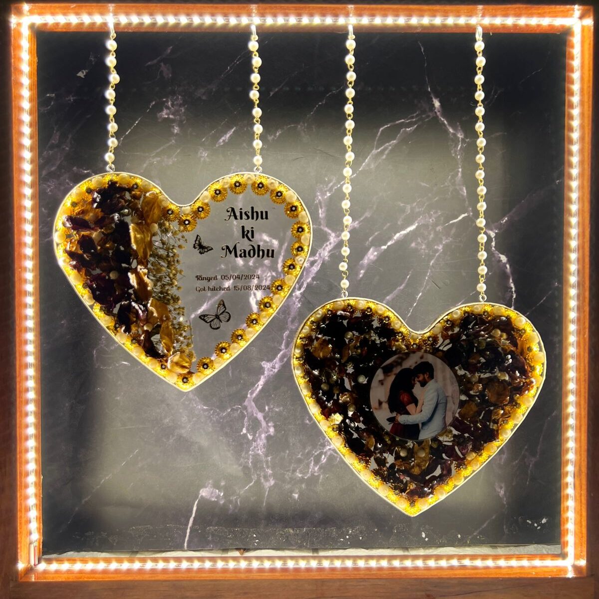 Heart-shaped wedding varmala preserved in a wooden LED frame.
