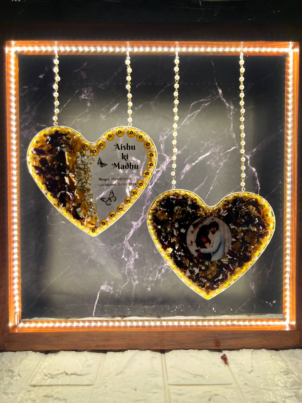 Heart-shaped wedding varmala preserved in a wooden LED frame.