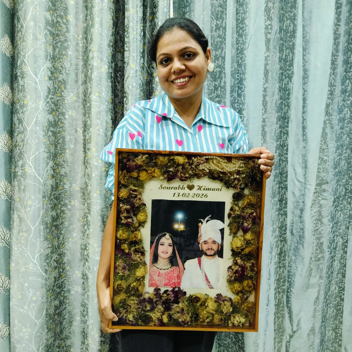 Kavita Dadhich holding a varmala frame with couple names and date