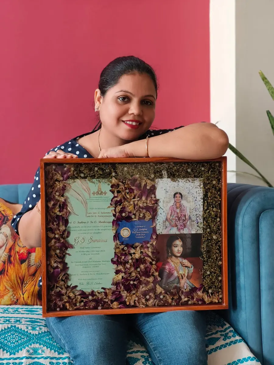 Kavita Dadhich with a varmala frame that holds the wedding card and photos